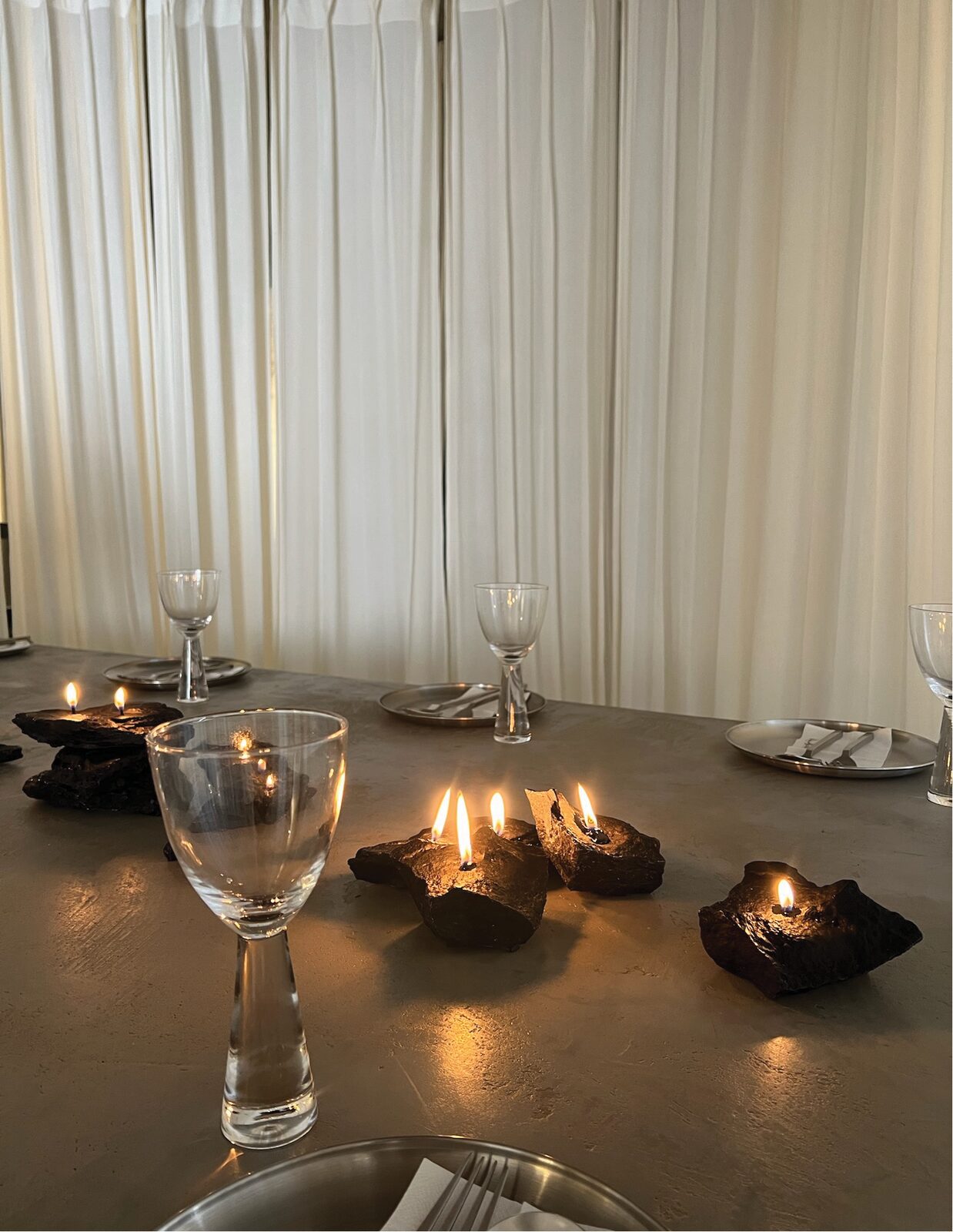 candles in dark vessels on the concrete table
