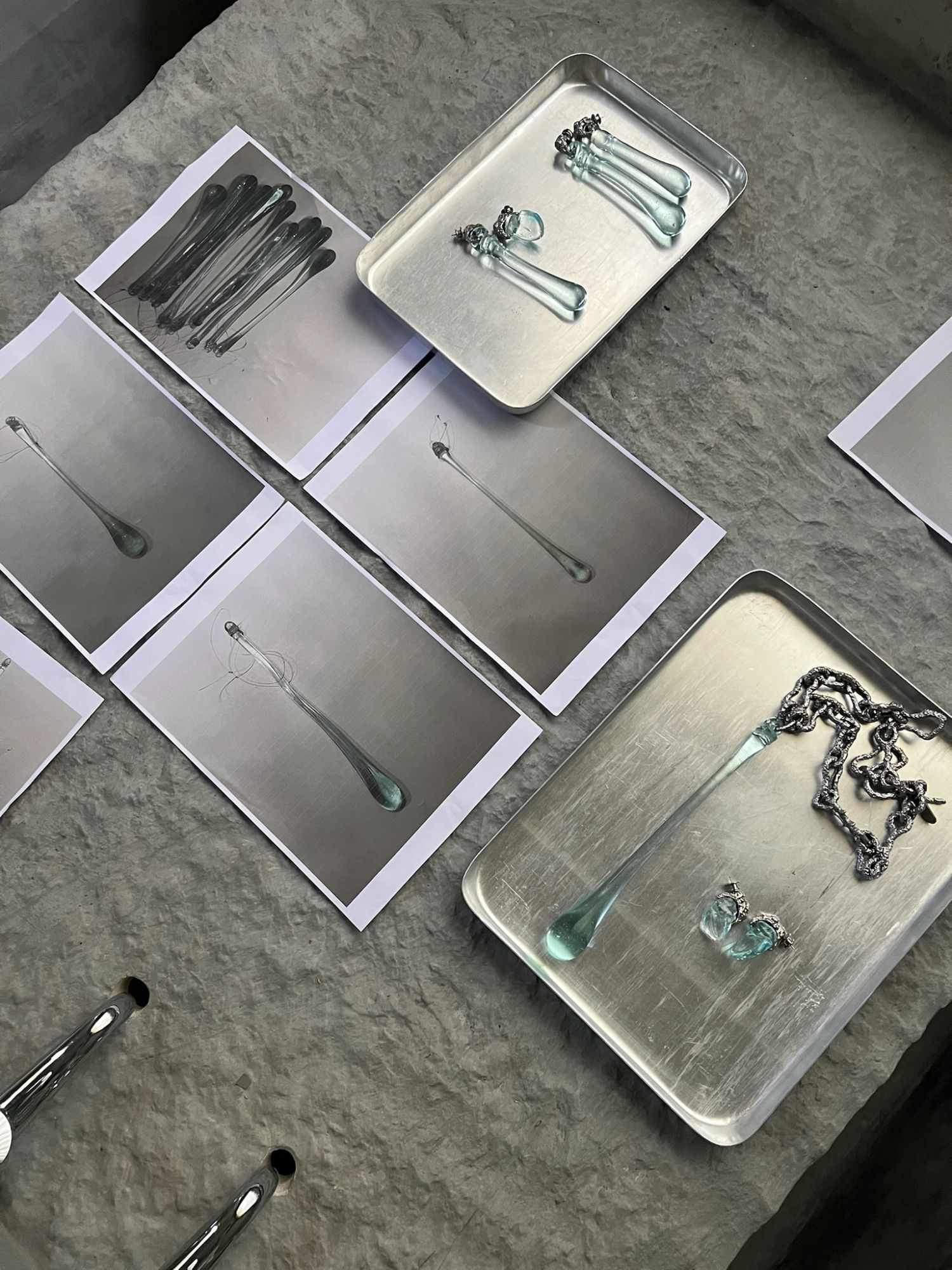 glass drops on steel trays among test prints, on the stone table