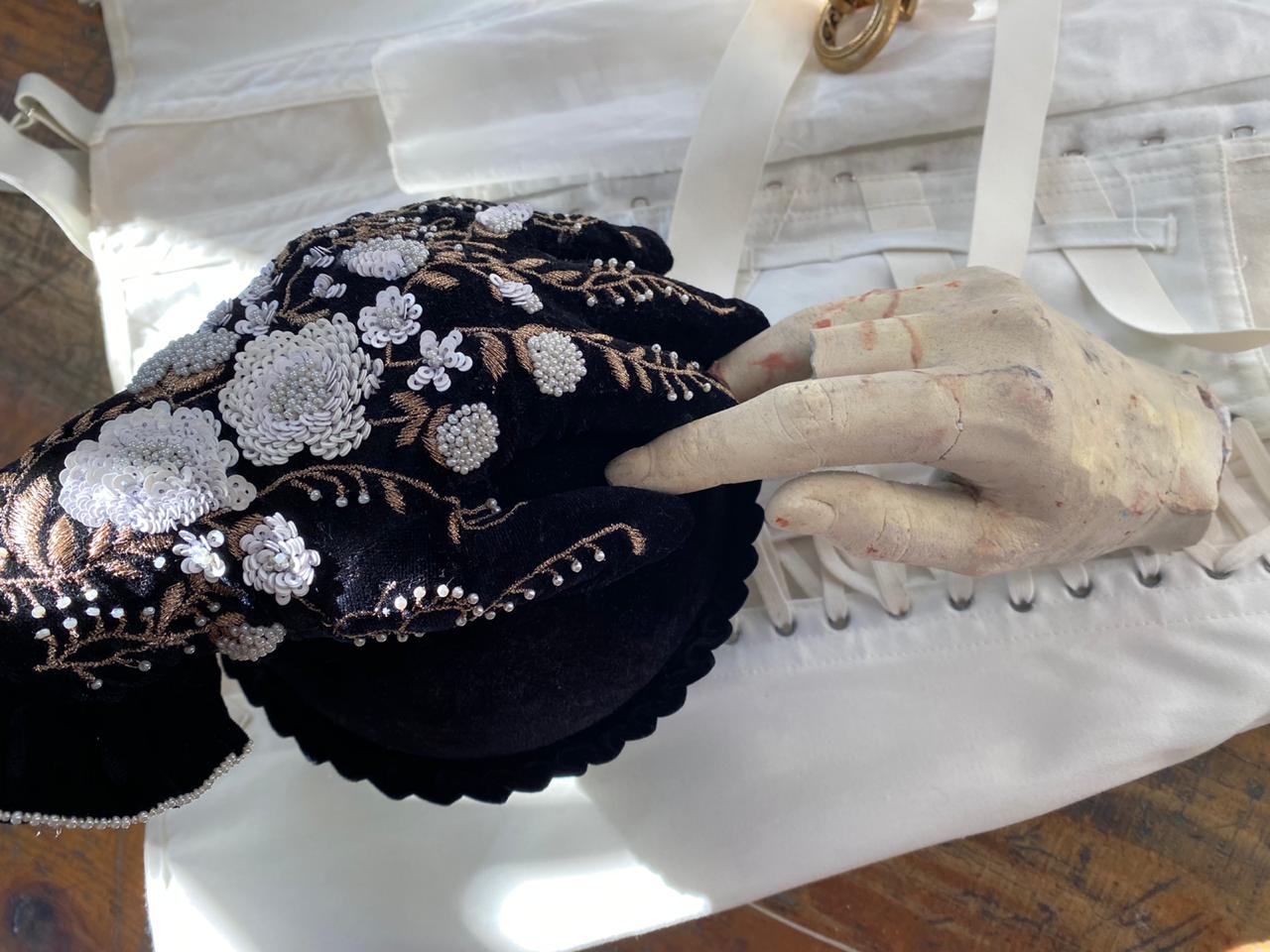 chrysalis: black velvet piece embroidered with pearls and white flowers, held by a mannequin hand