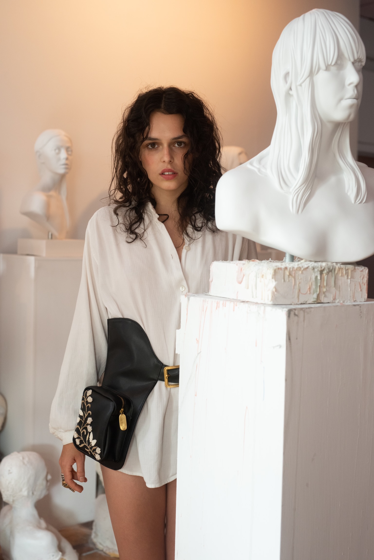 coercito: black leather holster belt with an embroidered pocket, worn over a white shirt