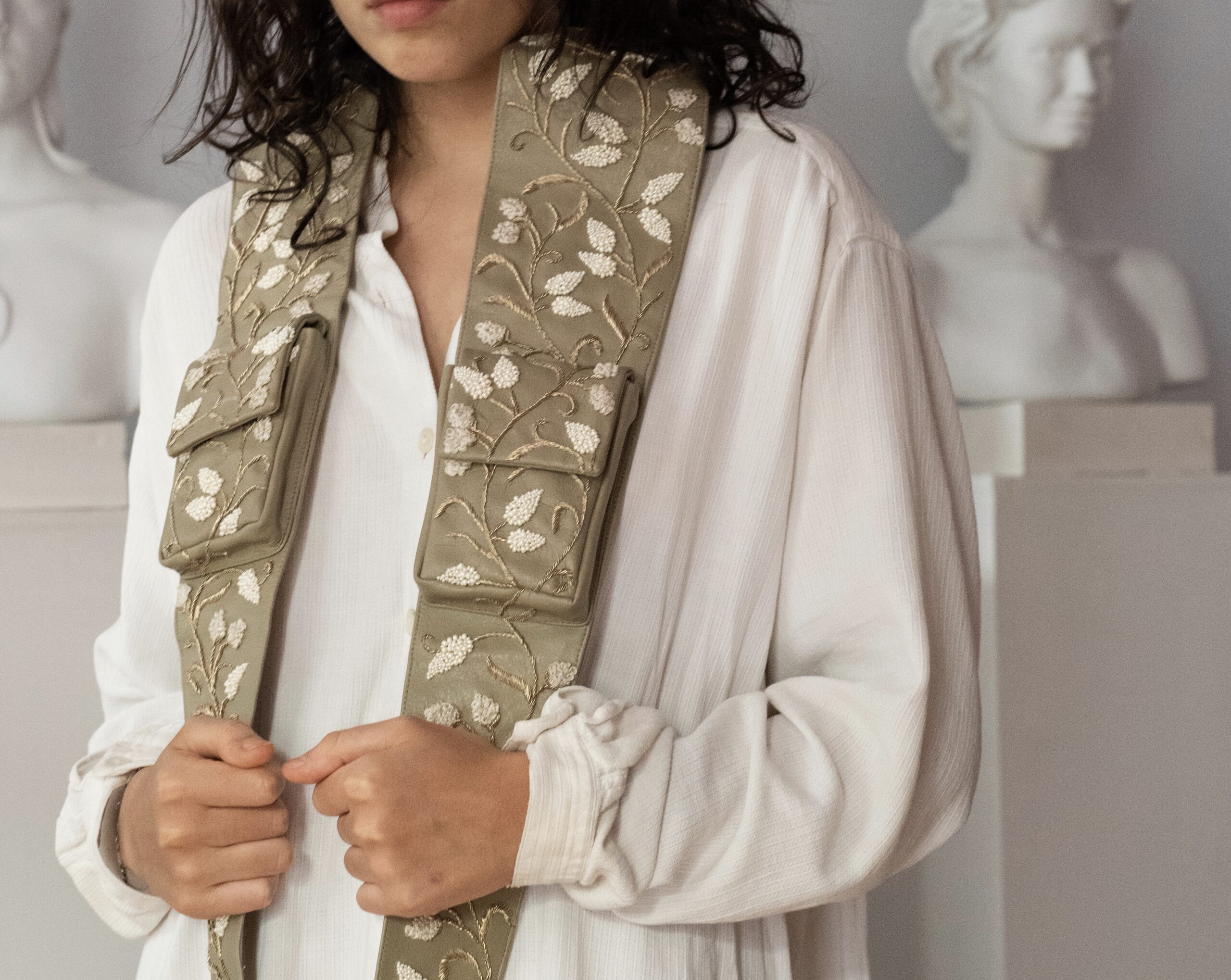 spero worn open over a white shirt, among plaster busts